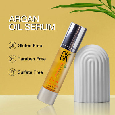 Argan oil serum bottle with silver cap on a yellow background. Text highlights features: gluten-free, paraben-free, sulfate-free. Green leaves accent.