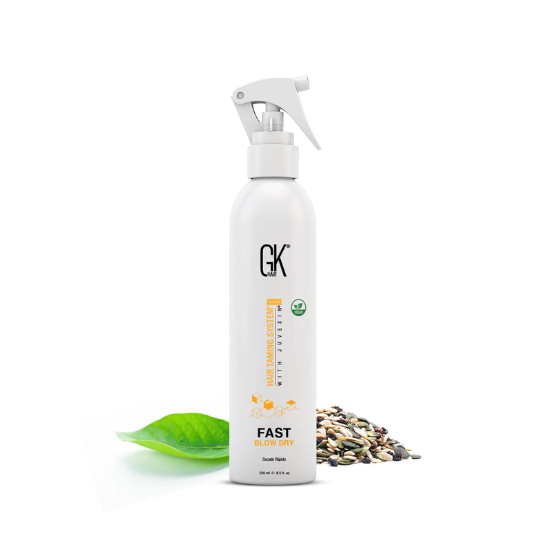 Bottle of GK Hair Fast Blow Dry spray, featuring a sleek design with a sprayer, alongside rich seeds and a green leaf.