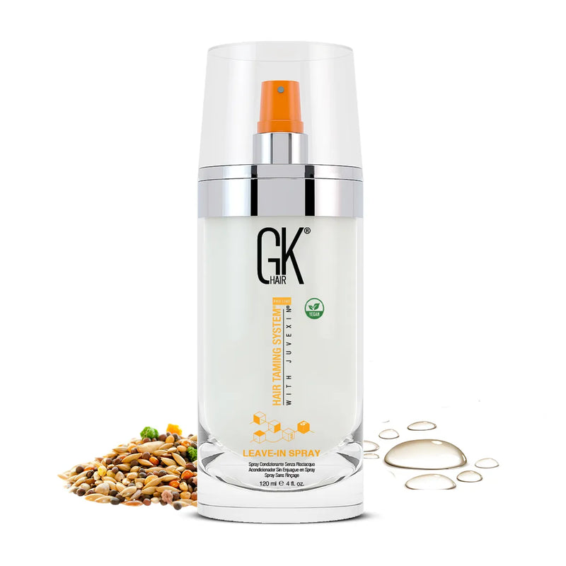 GK Hair Leave-In Spray 120 ml pump bottle with an orange nozzle, beside seeds and oil droplets, made with Juvexin
